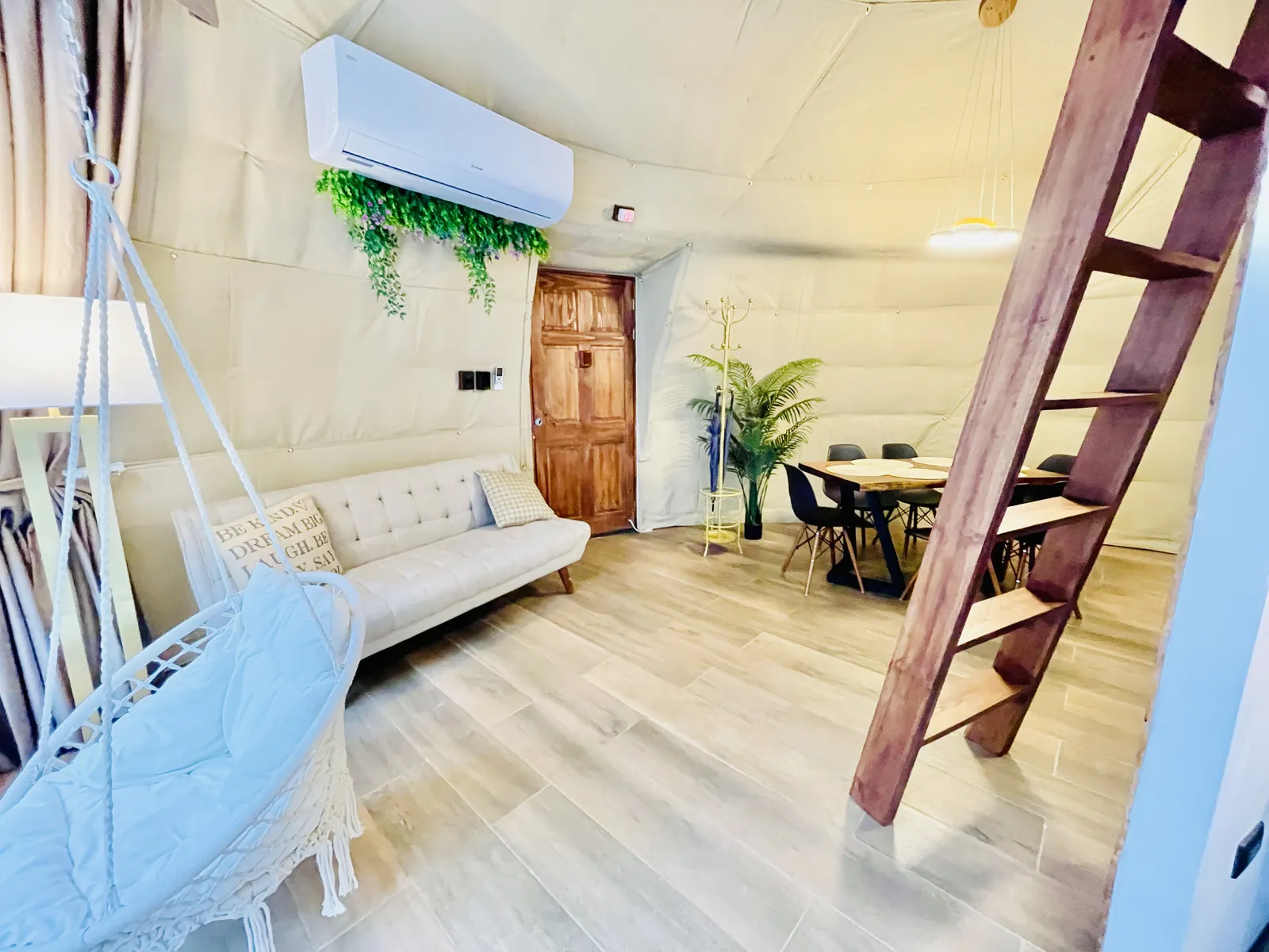 Interior de un domo con silla colgante y escalera al altillo